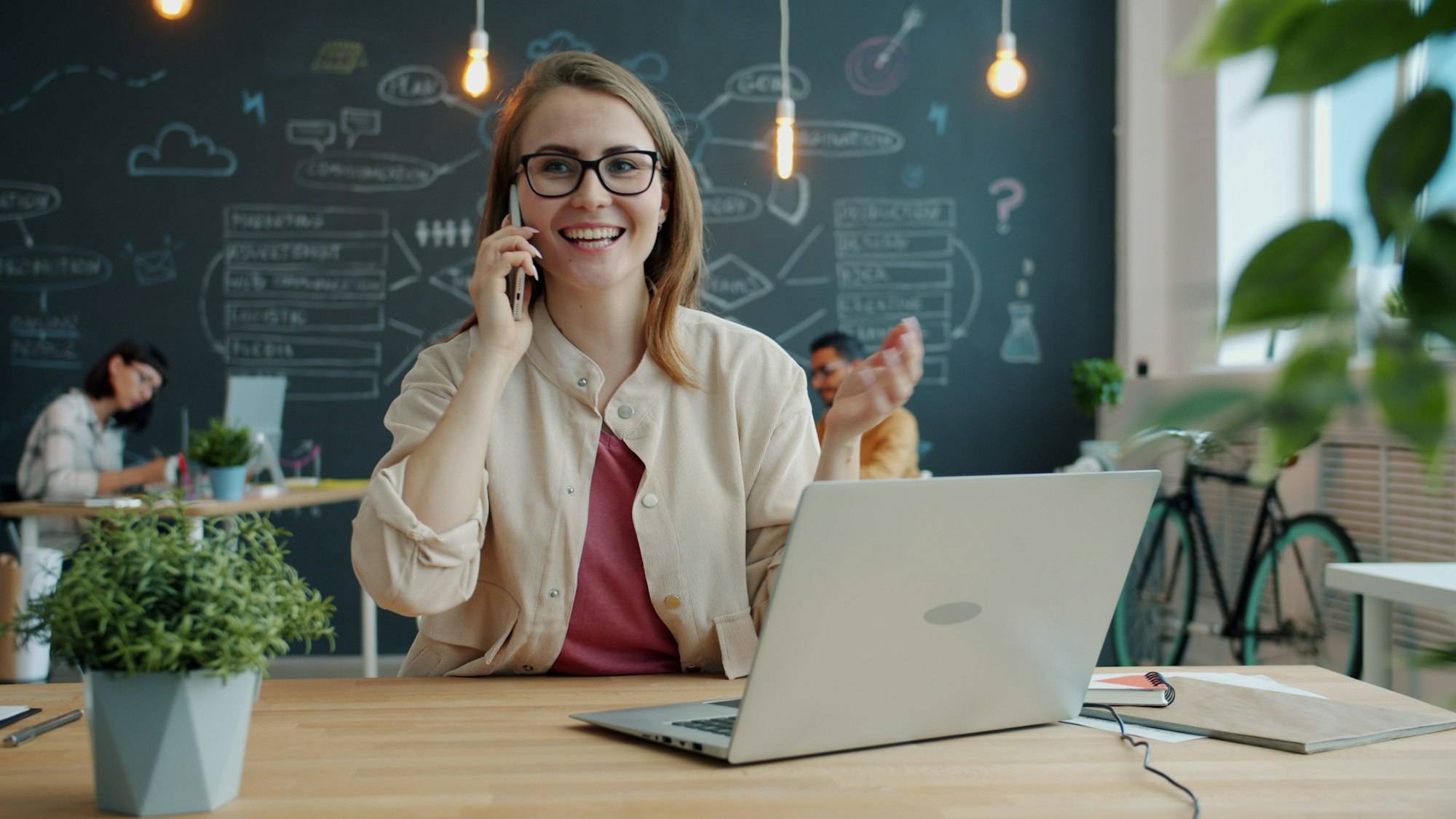 A business owner smiling while talking on her mobile phone at her desk