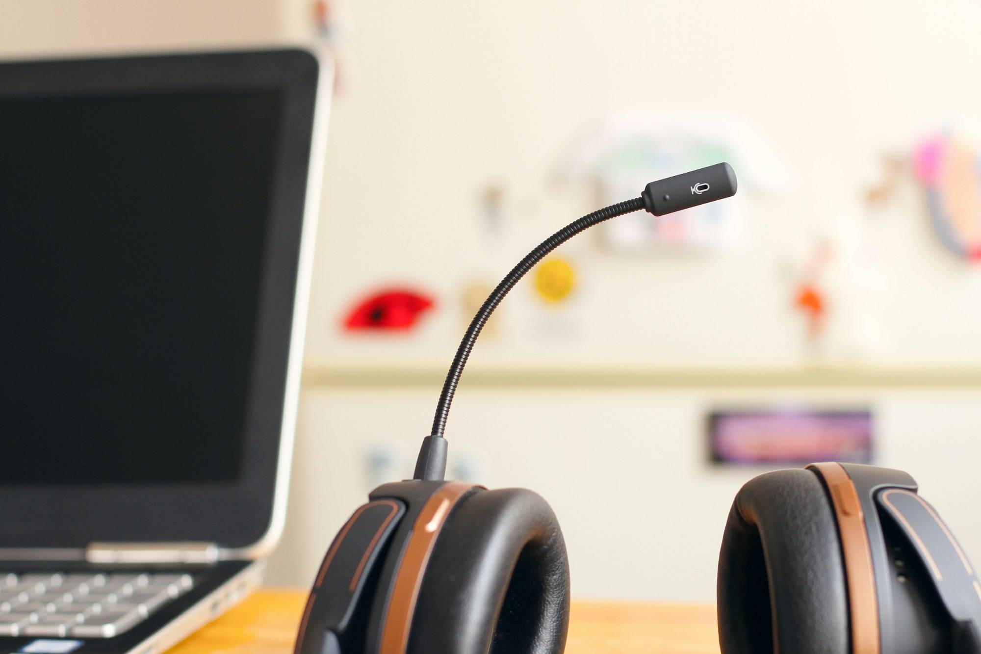 A black and brown call headset resting beside a laptop on a desk
