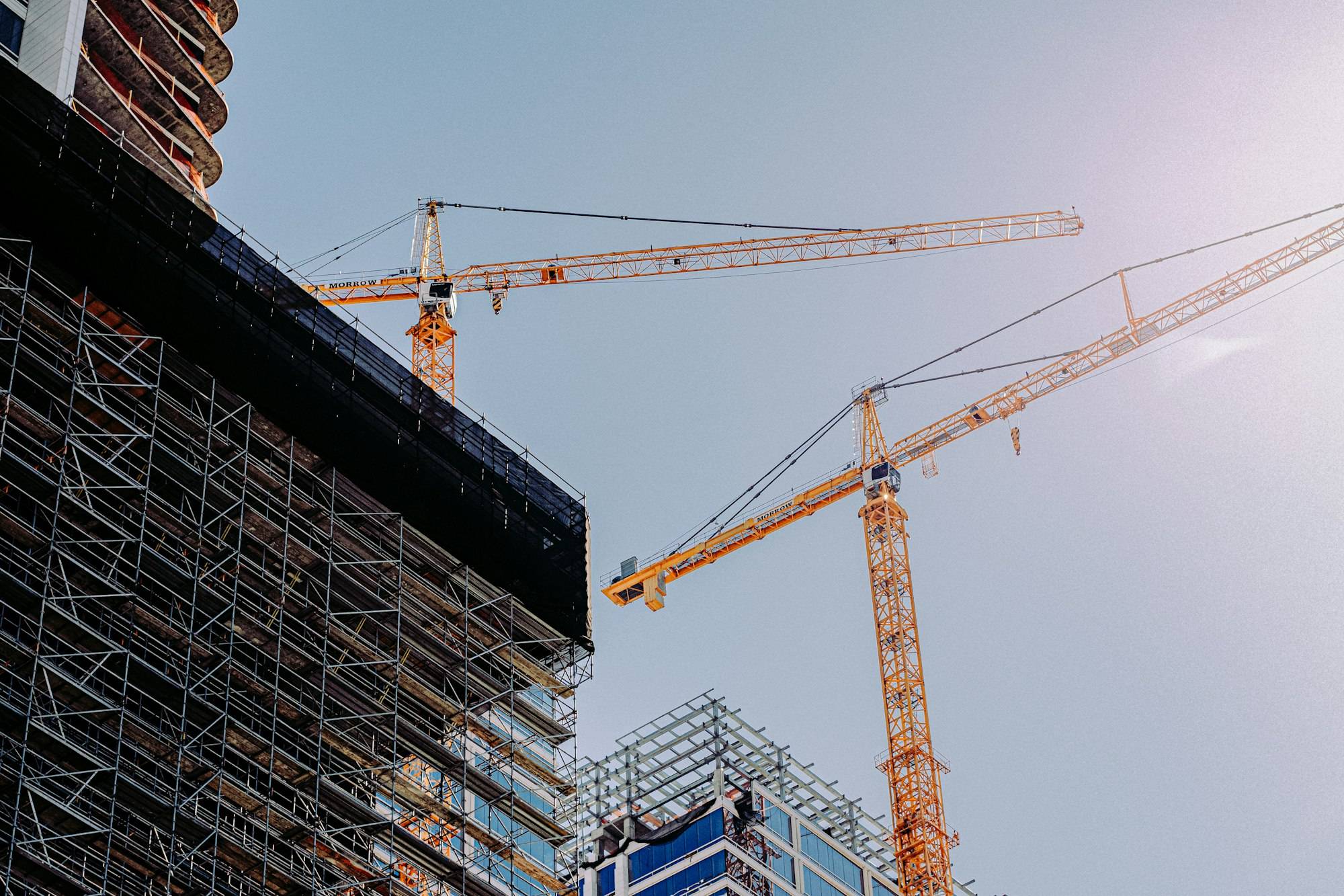 A yellow tower crane beside a building under construction