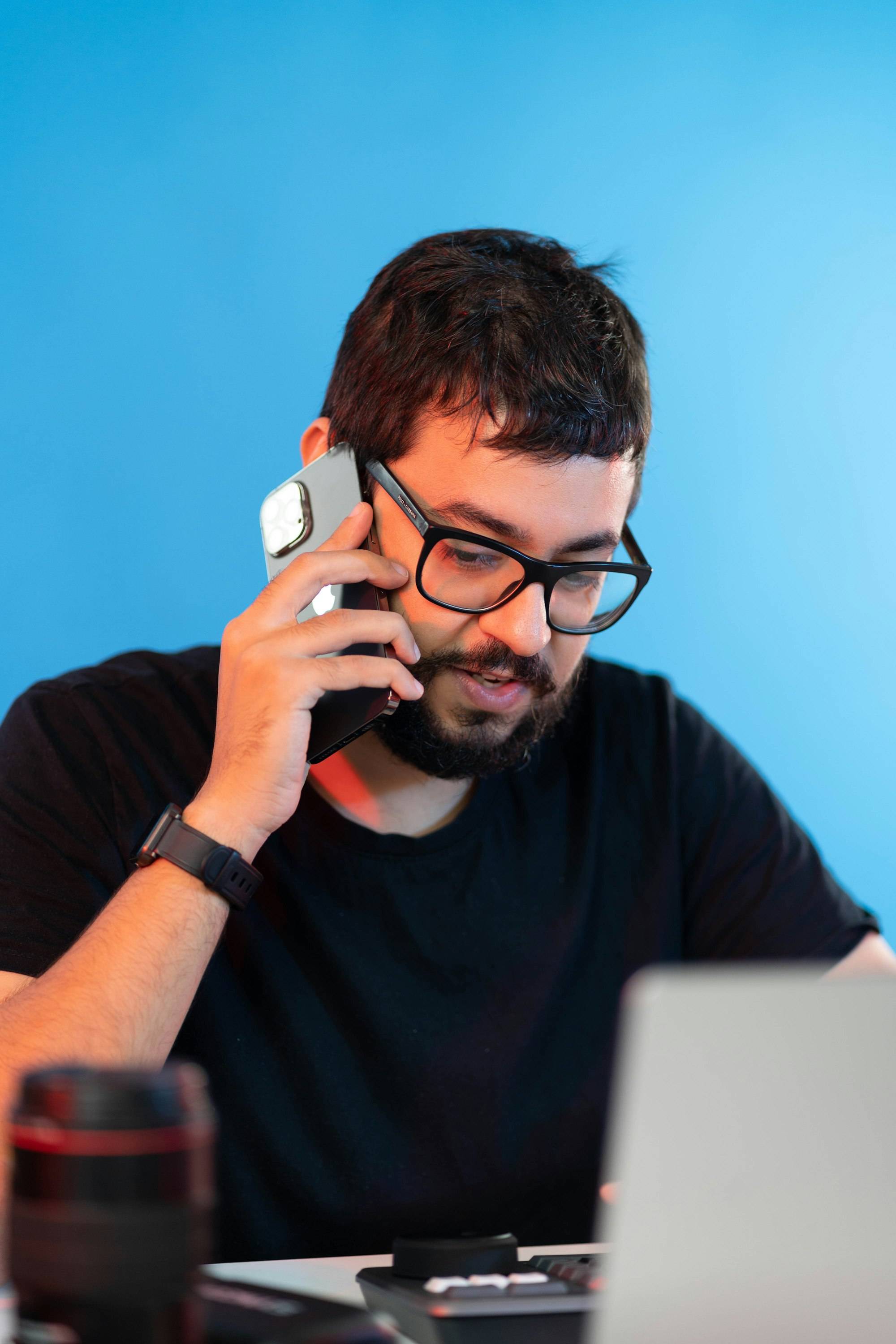 A man sitting at his desk talking on a mobile phone